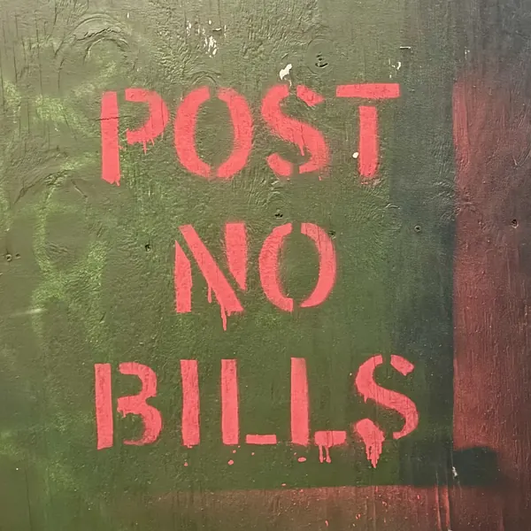 Red three-line stencil on hunter-green plywood, with heavy paint drips below the letters.